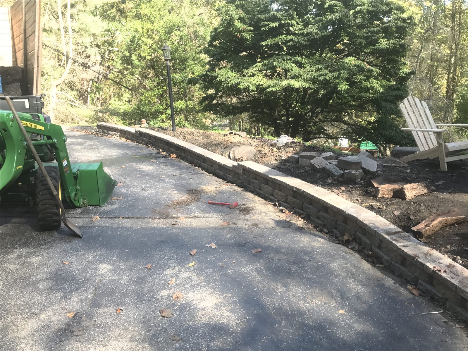 Retaining wall installation in progress with compact tractor on site